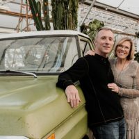 John and I posing in front of an antique green truck that was sitting in a garden nursery. Plants are in the background.