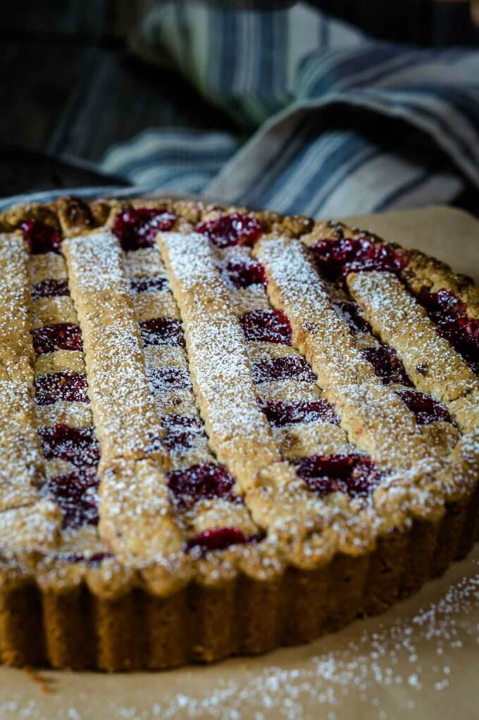 A baked raspberry linzer torte with a lattice top dusted with powdered sugar.