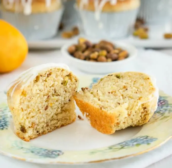 Lemon Pistachio Muffin sliced in half with a tender crumb and drizzled with lemon glaze