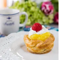 A puff pastry cup filled with lemon filling and whip cream