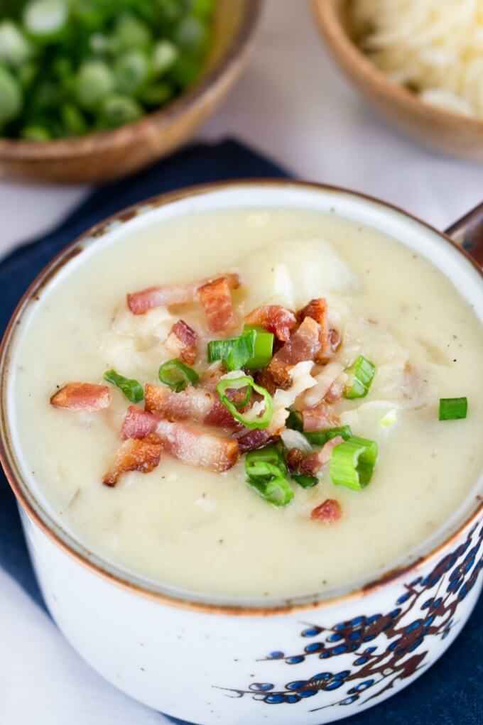 Thick Cheesy Baked Potato Soup loaded with green onions, bacon & cheese with extra bowls of cheese and onion