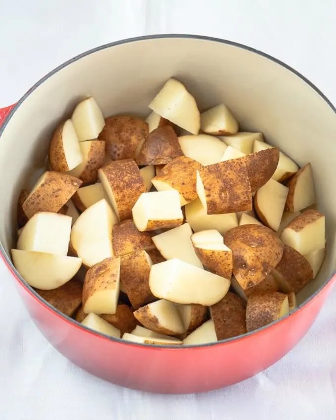 Large pot filled with unpeeled potatoes cubed into 2-inch pieces.