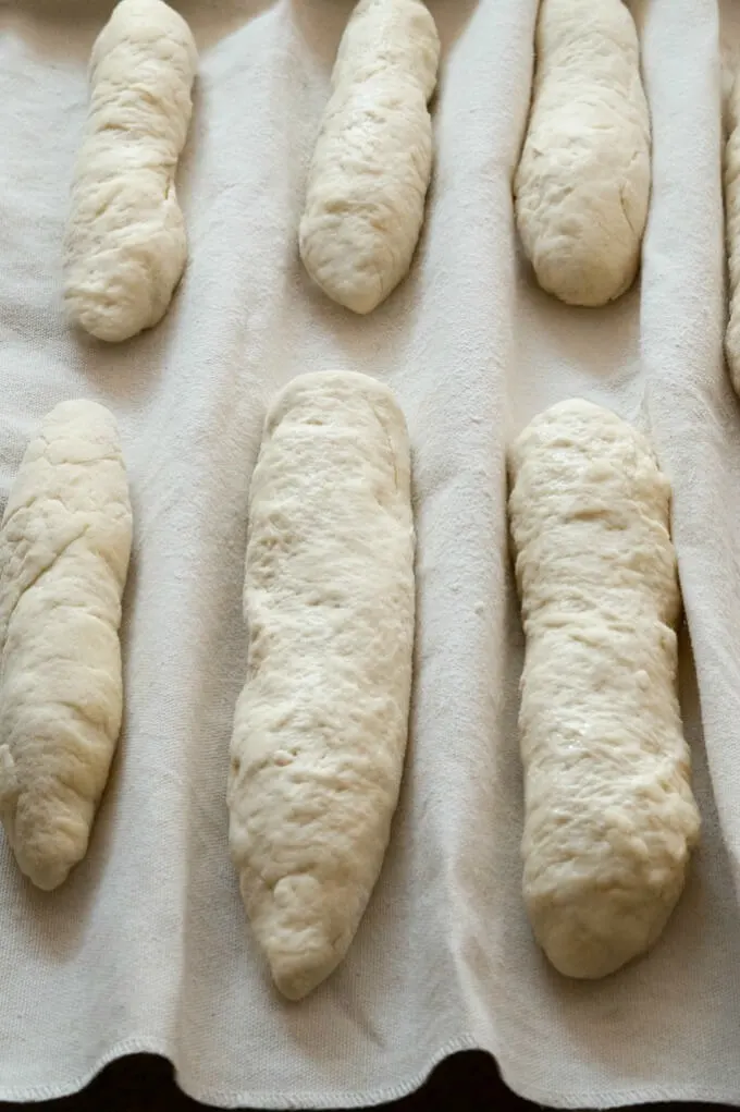 Dough is shaped into breadsticks and placed in a couche to rest