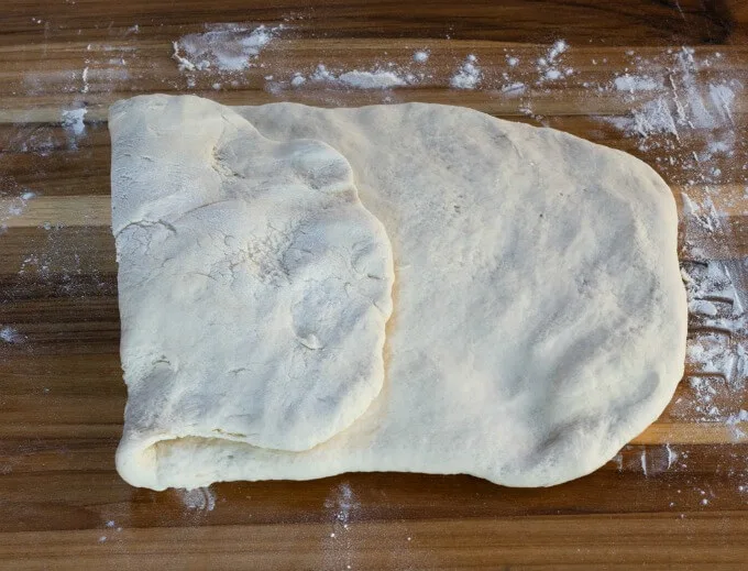 Ciabatta bread dough rolled flat with the first side folded to the center.