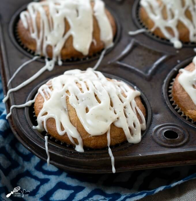 A mango muffin sitting in an antique tin drizzled with a vanilla bean glaze