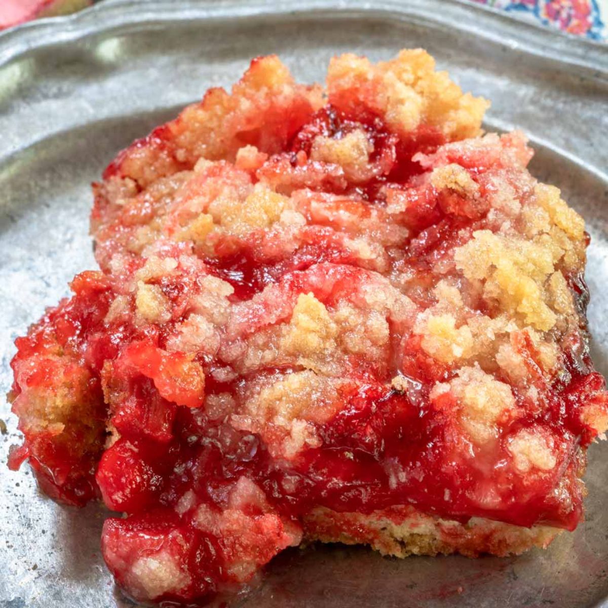 A front view of a slice of rhubarb dessert made with jello and a butter crumble top. Hostess At Heart