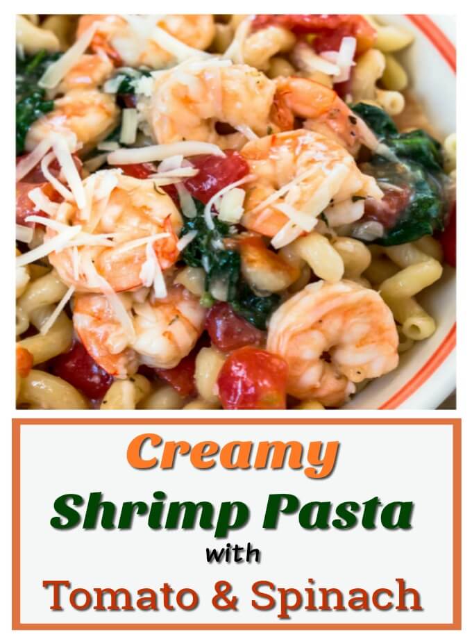Bowl of cavatappi pasta topped with shrimp, tomatoes, spinach and grated cheese