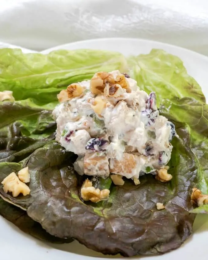 Scoop of Chicken Salad on a bed of lettuce and topped with chopped walnuts.