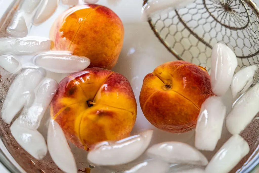 Fresh peaches submerged in ice water to remove the peel.