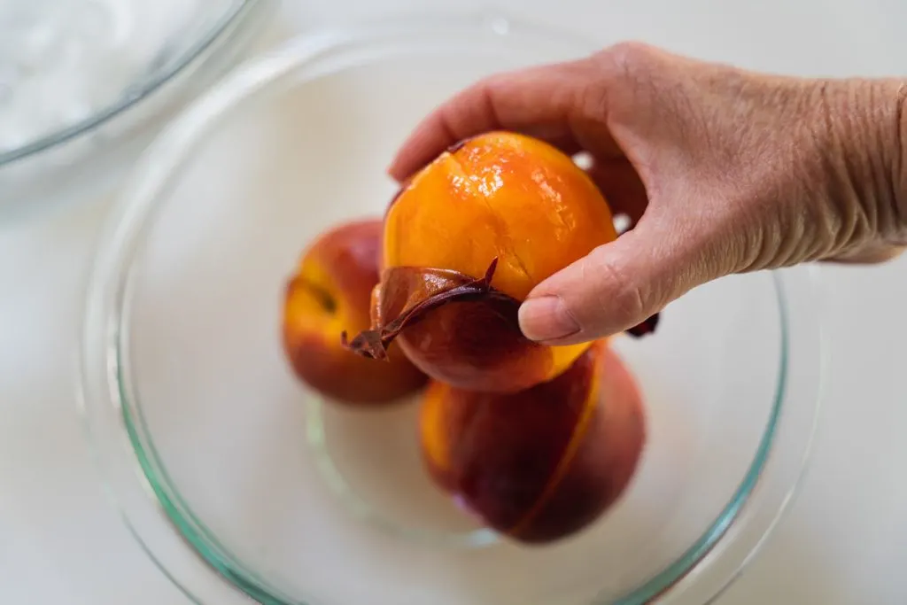 A fresh peach with the peel being removed.