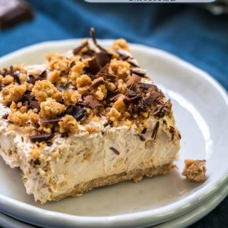 A square piece of peanut butter cheesecake sitting on a stack of two white plates and a blue napkin.