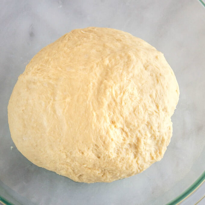 A ball of soft dough in a glass bowl.