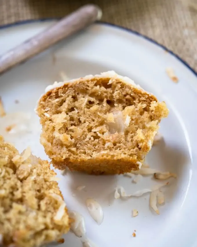 A muffin cut in half on a white plate showing pieces of fresh pears and a soft center.