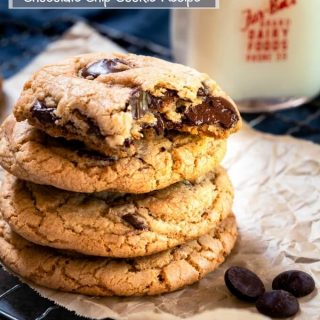 Stack of Chocolate Chip Cookies sitting on parchment paper with a bite taken out of the top one.