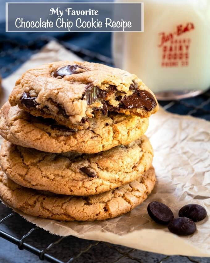 Stack of Chocolate Chip Cookies sitting on parchment paper with a bite taken out of the top one.