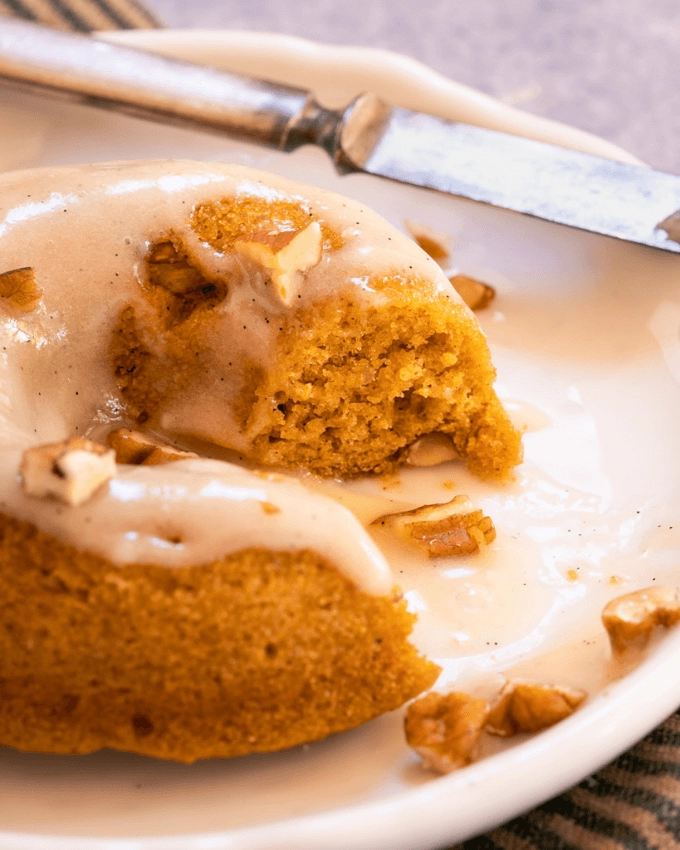 Pumpkin Donut with blaze and chopped pecans with a section cut out showing the center.