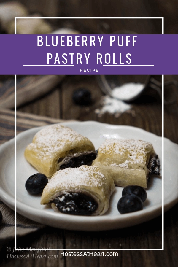 Three blueberry puff pastry rolls on a white plate with the title \"Blueberry Puff Pastry Rolls\"  printed across the top of the photo.