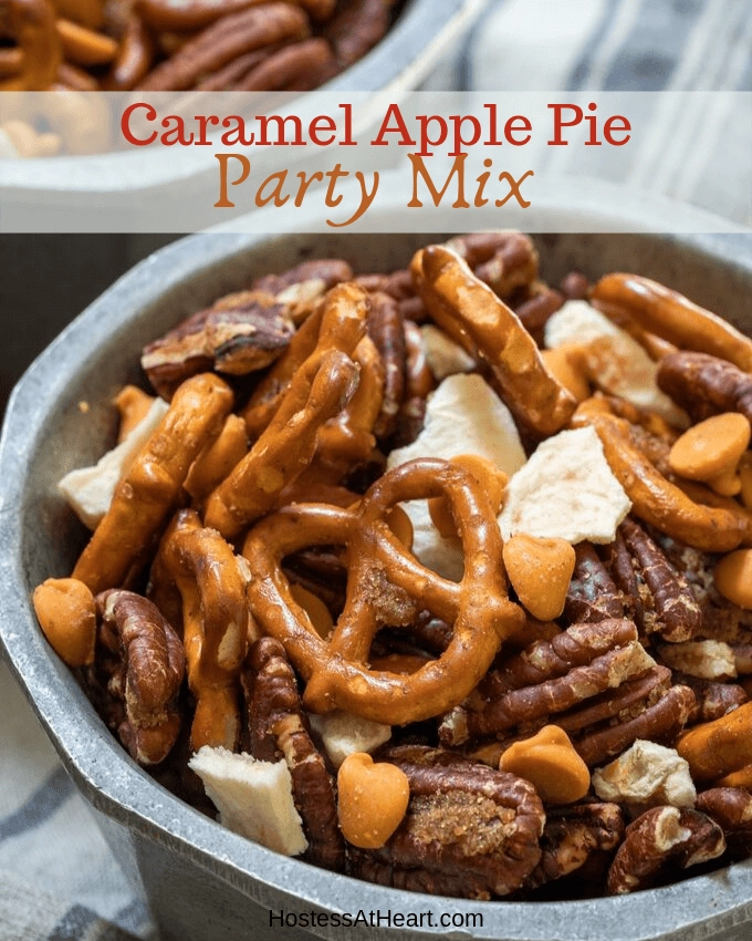 Close up view of pretzels, pecans, caramel chips and dried apples mix in a bowl on a blue striped napkin