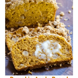 A slice of pumpkin bread dotted with chunks of apple and streusel topping with melted butter running down the slice over a wooden cutting board.