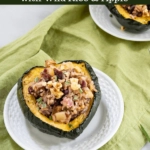 Half of an Acorn Squash stuffed with wild rice and apples on a white plate sitting over a green napkin with the recipe title over the top.