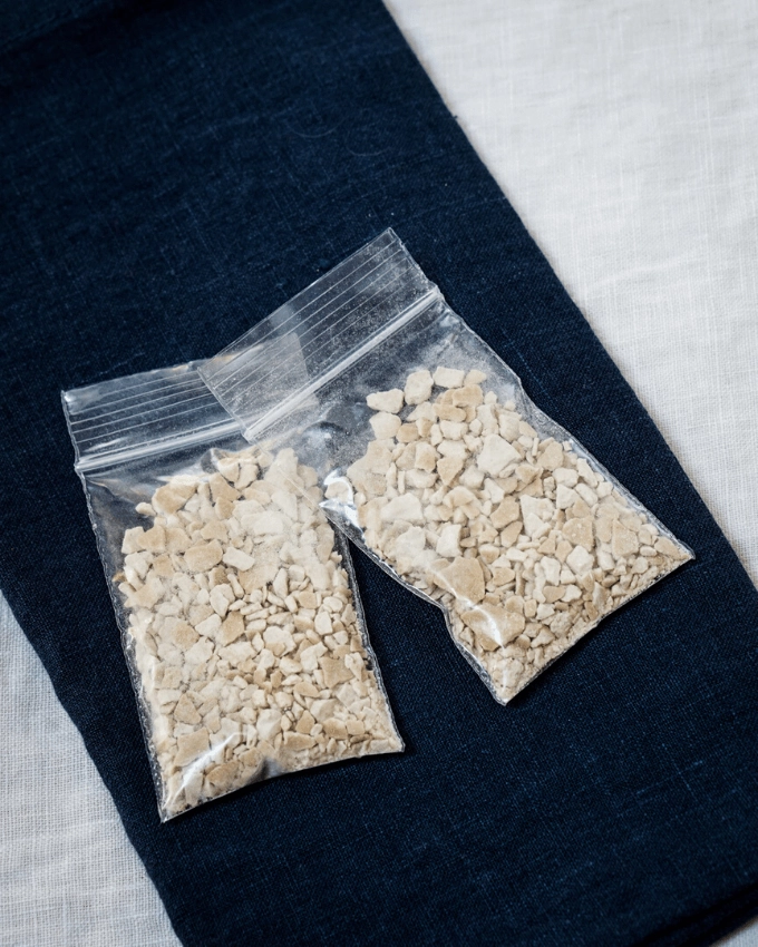 Two plastic bags filled with dried bread starter sitting on a navy blue napkin