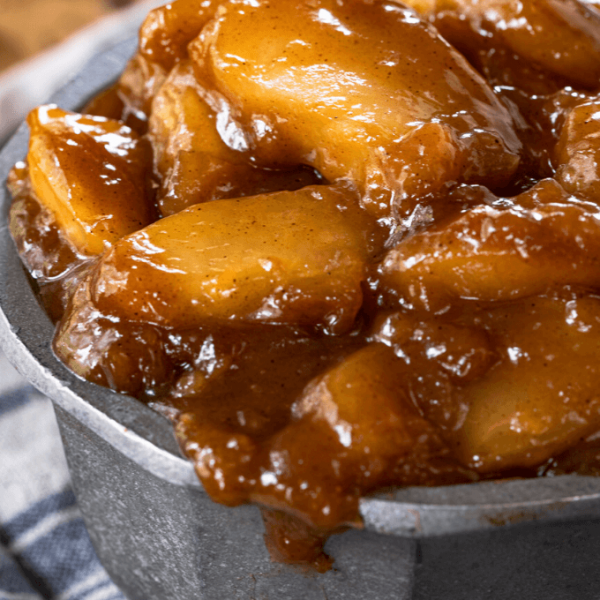 Straight on view of apples in brown sugar-cinnamon sauce overflowing a metal bowl.