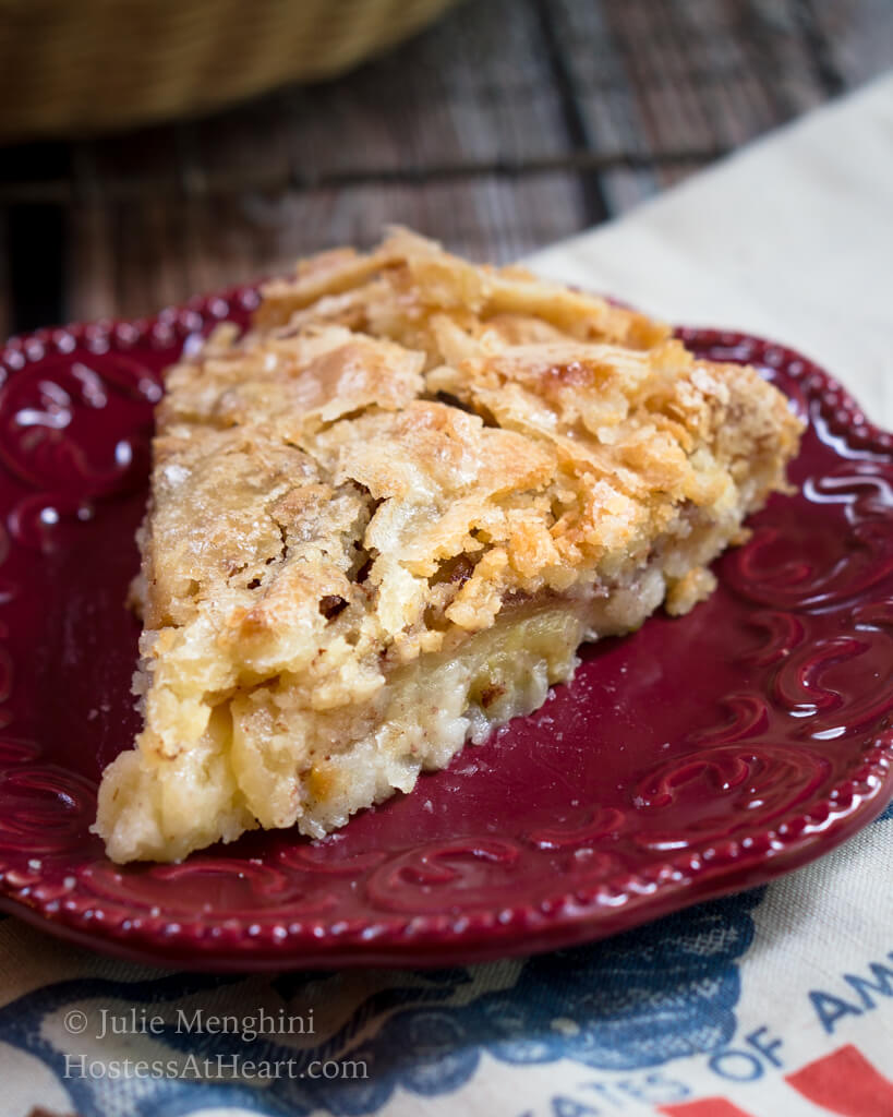 A slice of Swedish apple pie with a flaky top on a red plate.
