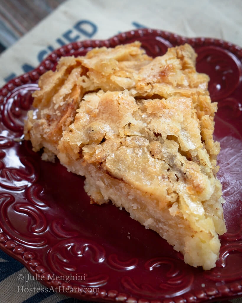 Top view of a slice of Swedish Apple Pie with a flaky top on a red plate