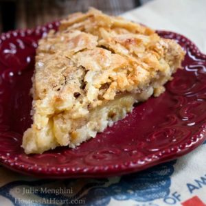 A slice of Swedish apple pie with a flaky top on a red plate.