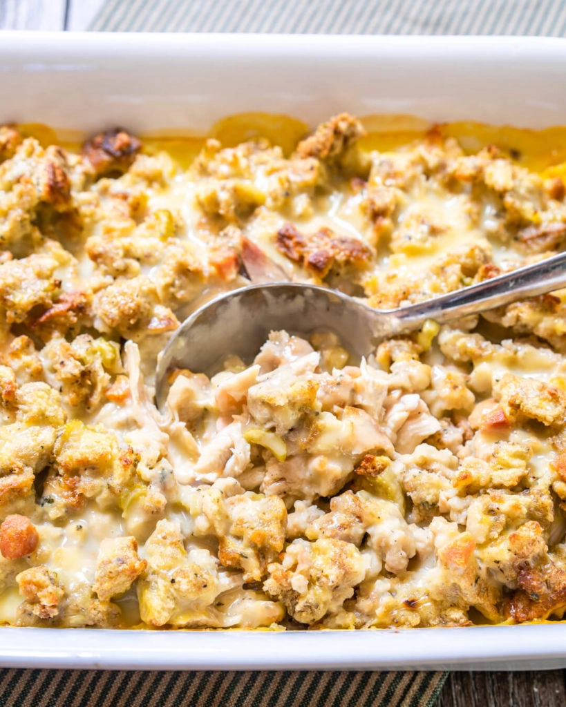 3/4 view of a turkey casserole in a white dish showing creamy turkey and dressing with a spoon dipping in.