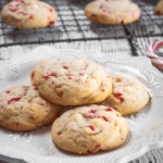 Stack of four cookies on a white plate with a cooling rack filled with cookies behind it.