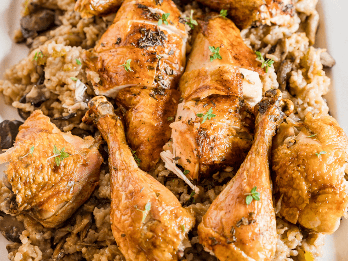 Close up top view of roasted chicken sitting on a creamy bed of mushroom risotto and garnished with fresh thyme leaves