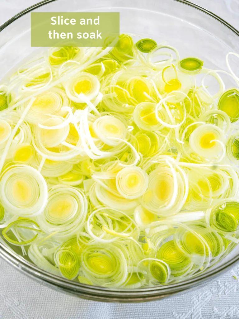 A bowl of water filled with sliced leek titled slice and soak.