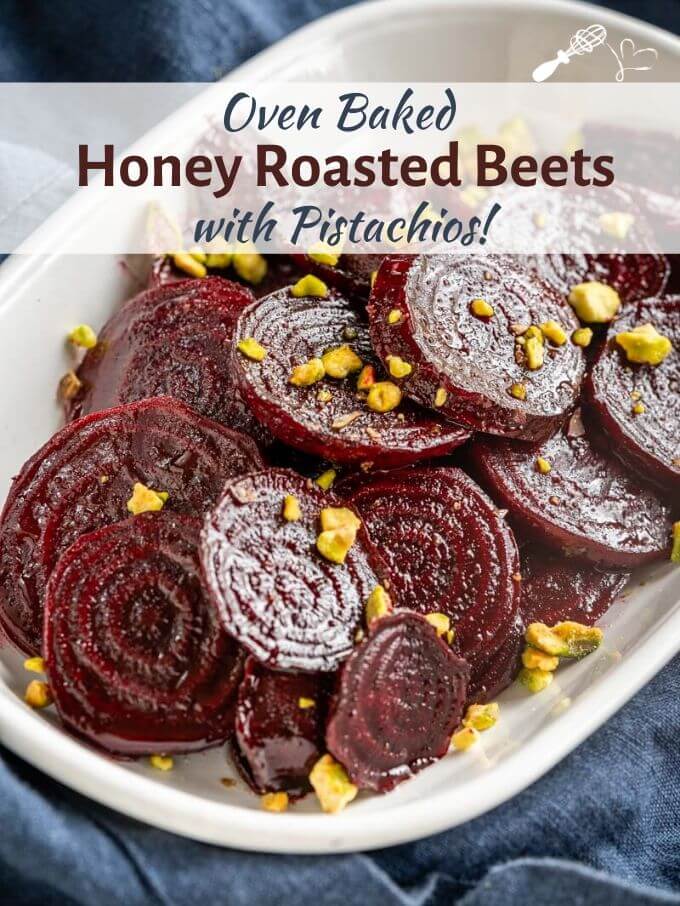 Close-up angle photo of glistening red beet slices in a white bowl sprinkled with chopped pistachio nuts. The title banner \"Oven Baked Honey Roasted Beets with Pistachios runs across the top.