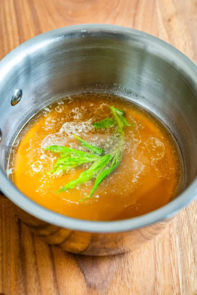 A small saucepan filled with the tarragon glaze ingredients of sherry, honey, butter and tarragon.