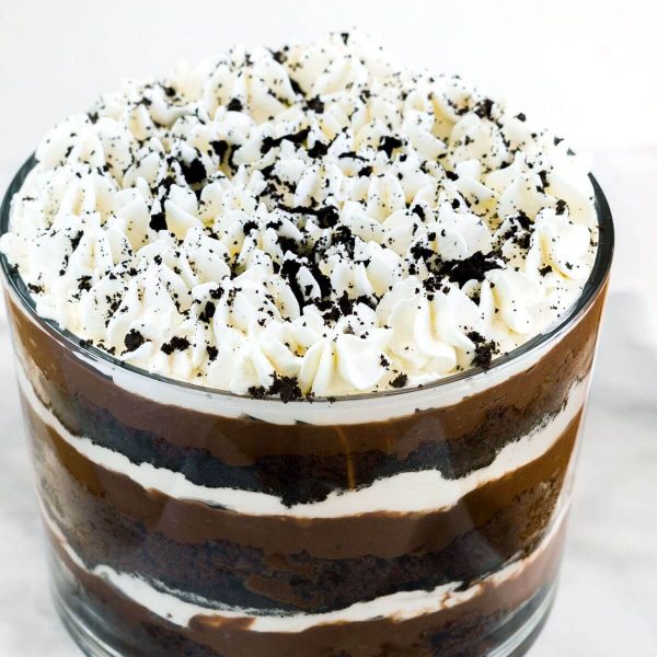 Top angle photo of a chocolate cake trifle showing several layers of cake, pudding, whipped cream and cookie crumbs in a tall trifle bowl.
