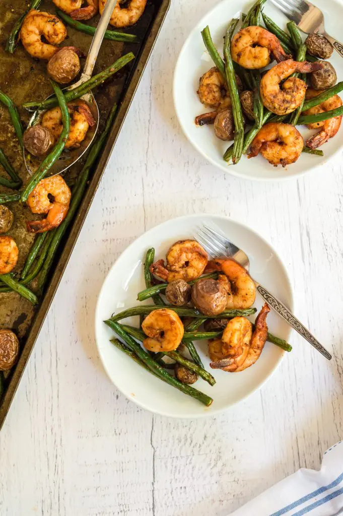 Top down view of plates full of cooked shrimp, green beans, and potatoes.