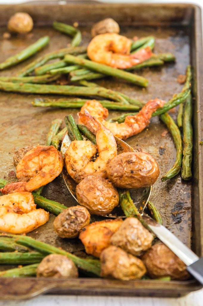 Sheet pan filled with cooked shrimp, green beans, and potatoes