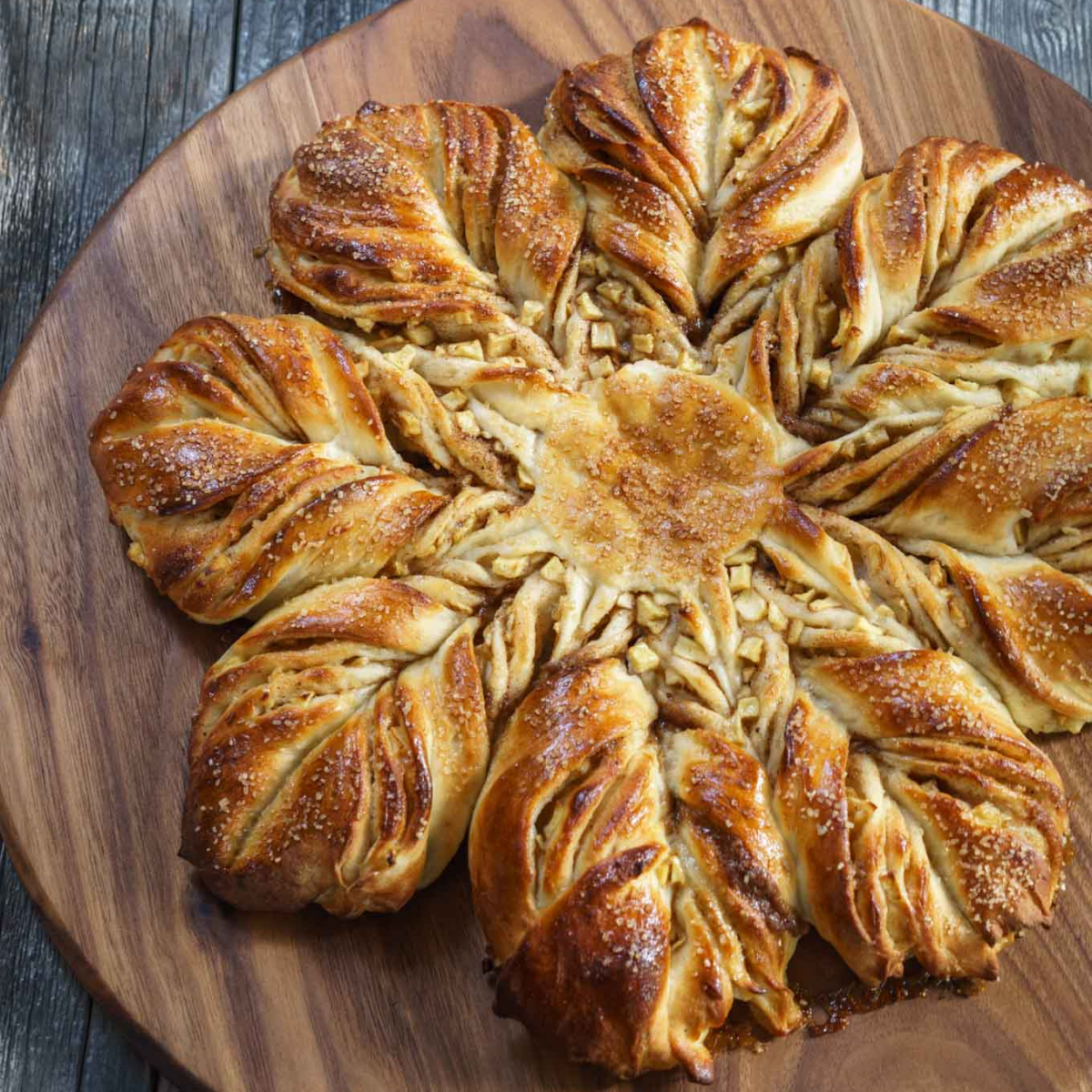 A top-down photo of a star shaped loaf of bread on a wooden cutting board.