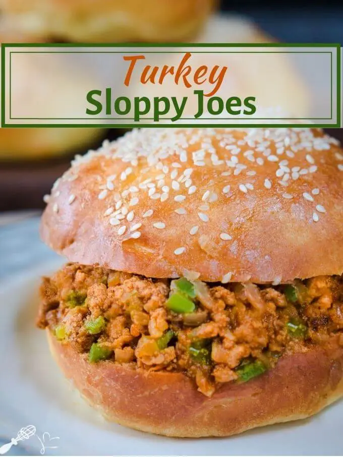 Sideview of a turkey sloppy joe dotted with green pepper in a sesame seed bun sitting on a light blue plate. The title "Turkey Sloppy Joes" run across the top.