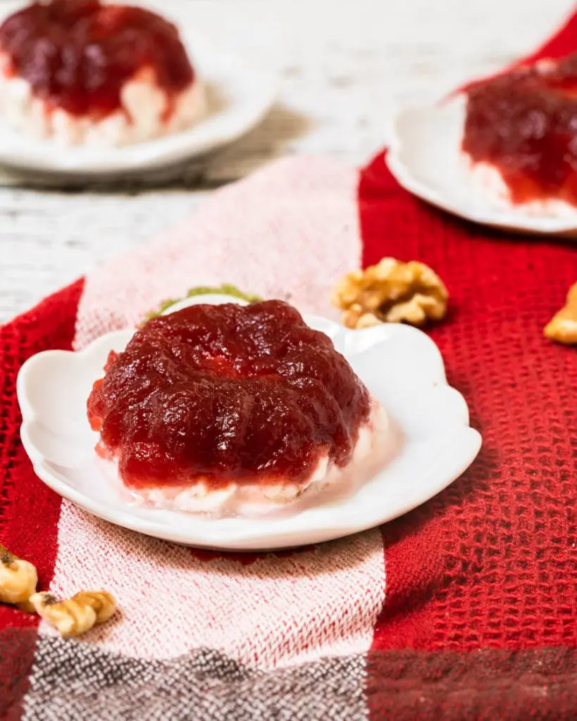 A Frozen Cranberry Salad on a white plate sitting over a red striped towel. Two more salads sit in the background.