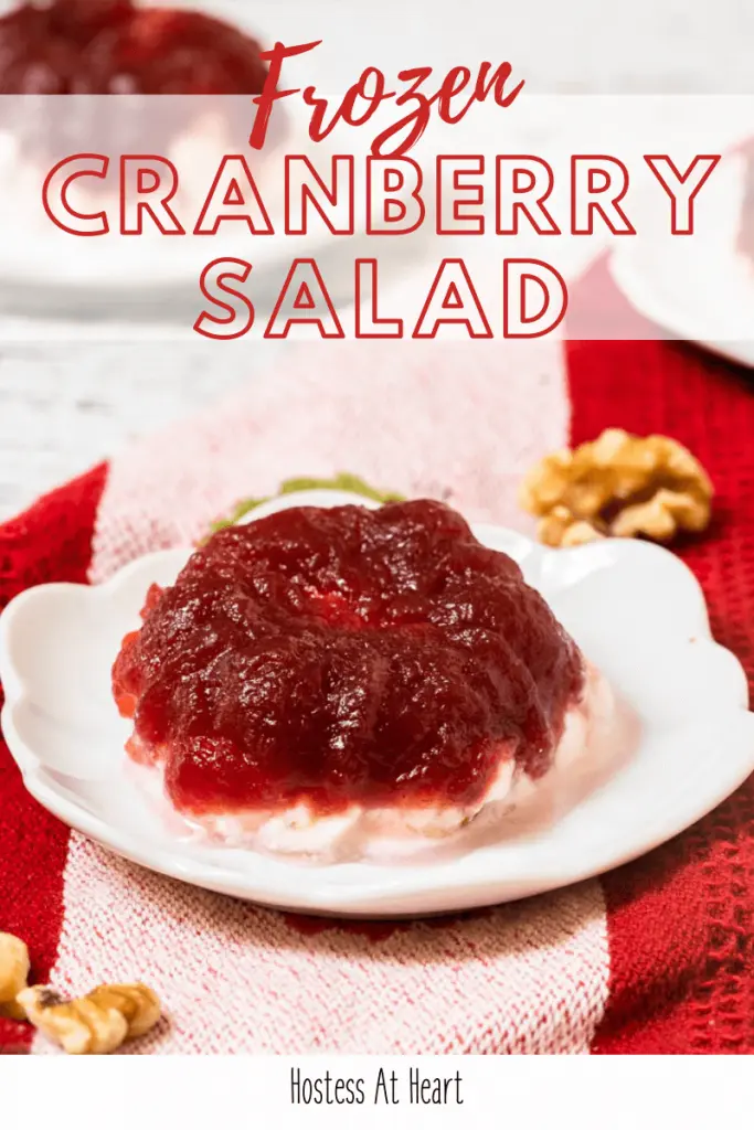 3/4 angled of a molded Frozen Cranberry Salad sitting on a white plate over a red striped towel.