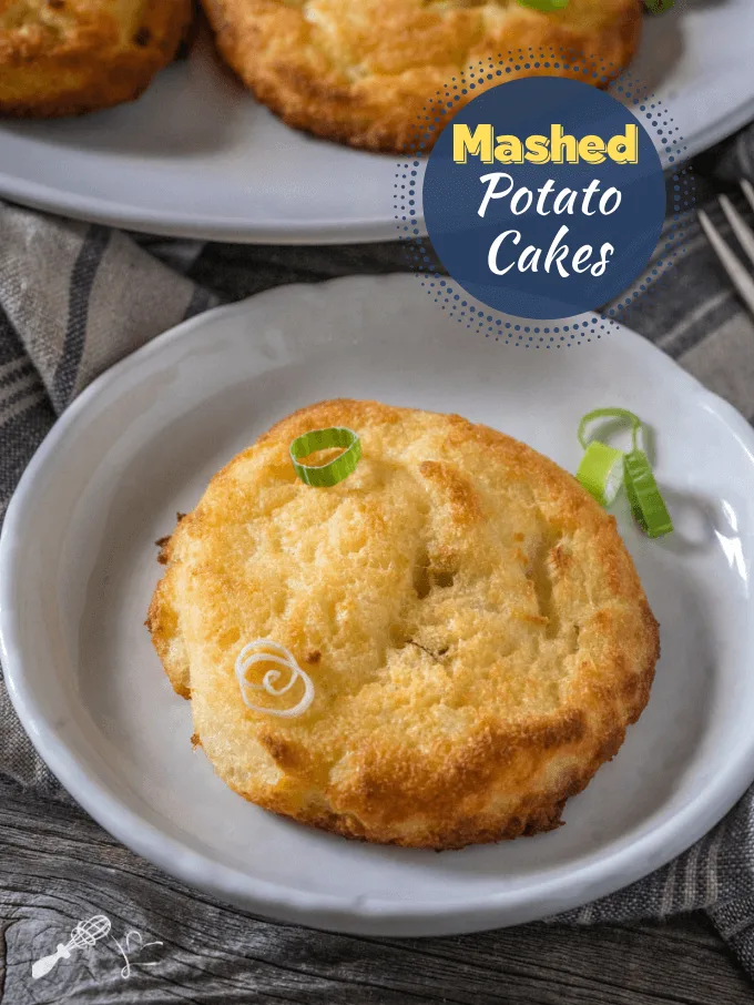 Potato cake sitting on a gray plate topped with sliced green onions over a gray stripped napkin.