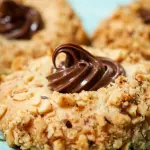 Close-up sideview photo of a Nutella Filled Hazelnut Thumbprint cookie.