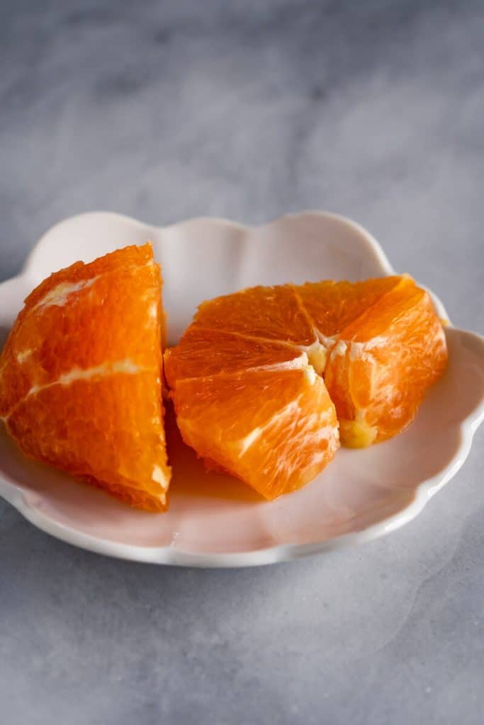 Small white plate holding a sliced orange.