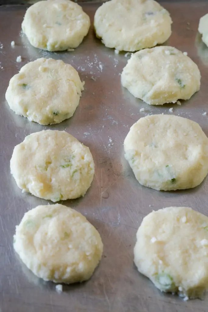 Raw potato patties on a baking sheet.