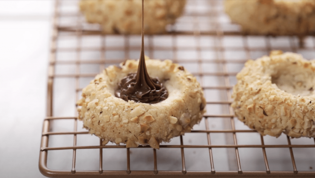 Angled view of a Hazelnut Thumbprint cookie being filled with Nutella.