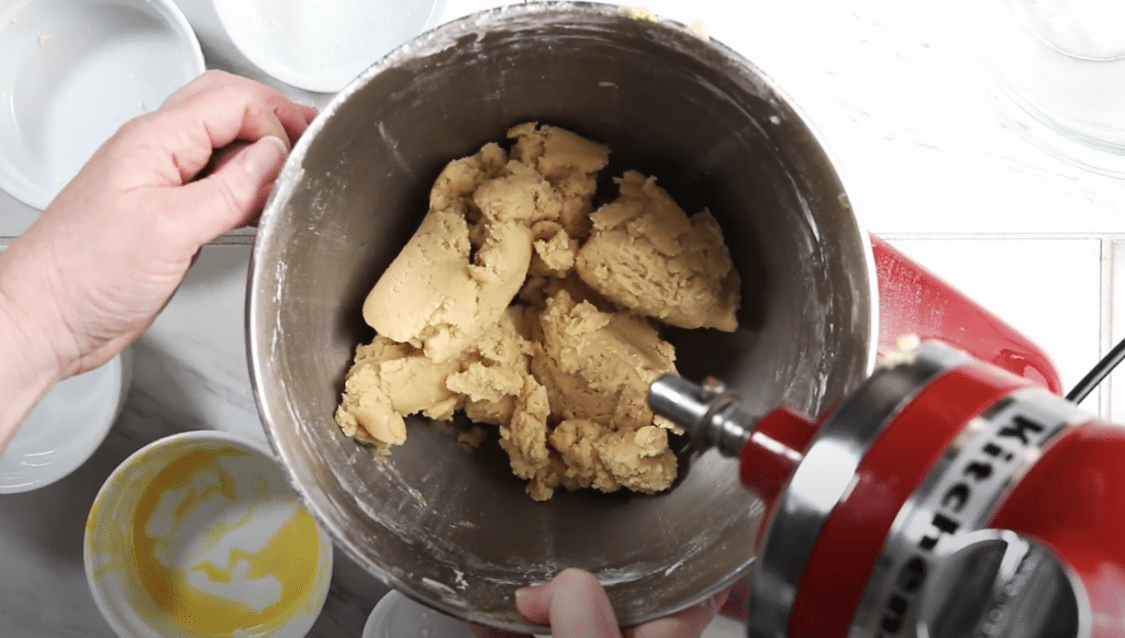 Thick cookie batter in the bowl of an electric mixer.