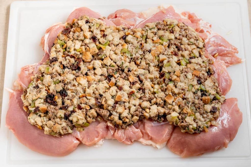 A butterflied turkey breast with stuffing spread over the top.