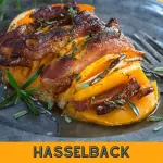 Butternut squash sliced and baked with apple, bacon, and rosemary on a metal plate.